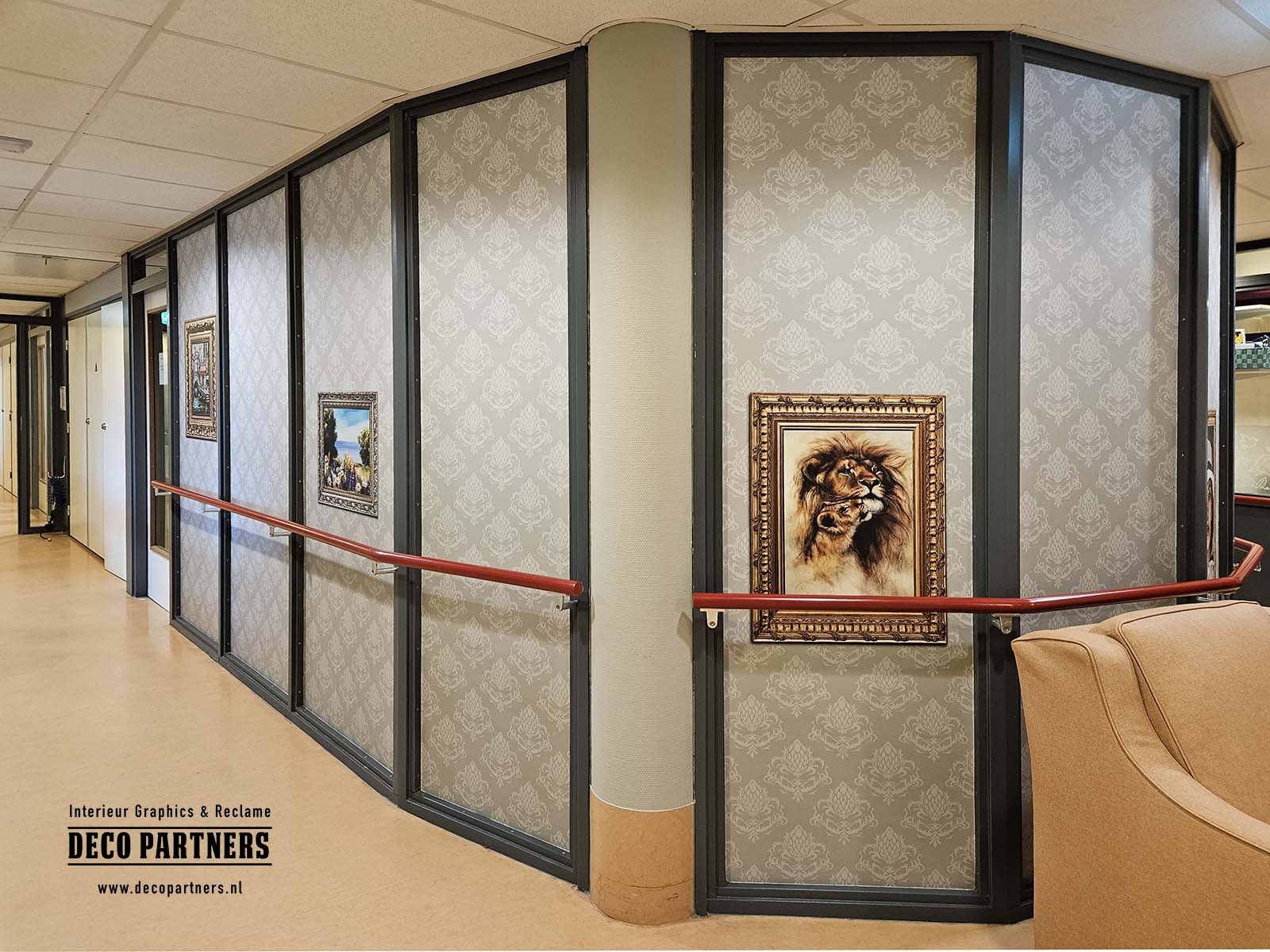 Overzicht van brandveilige wandbestickering in zorginstelling met klassiek behangpatroon en geïntegreerde schilderijen, toegepast op glazen wanden voor een rustige en huiselijke uitstraling