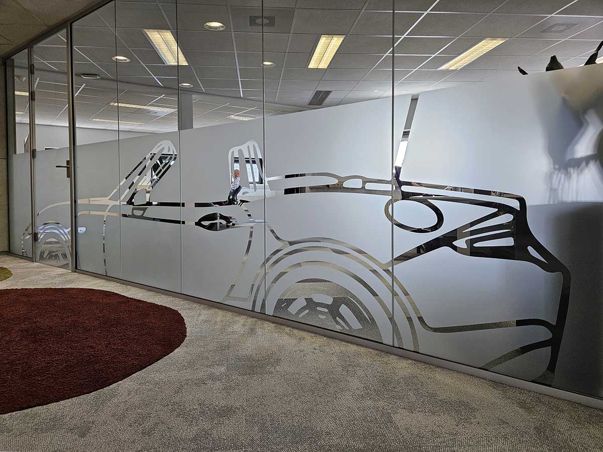 Zandstraalfolie met uitgesneden autovorm op glazen kantoorwand, decoratief en functioneel voor privacy en merkbeleving