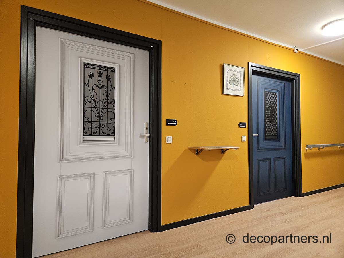 Deurstickers op een afdeling voor mensen met dementie zijn duidelijke herkenningspunten, zodat bewoners hun kamer makkelijker terugvinden.