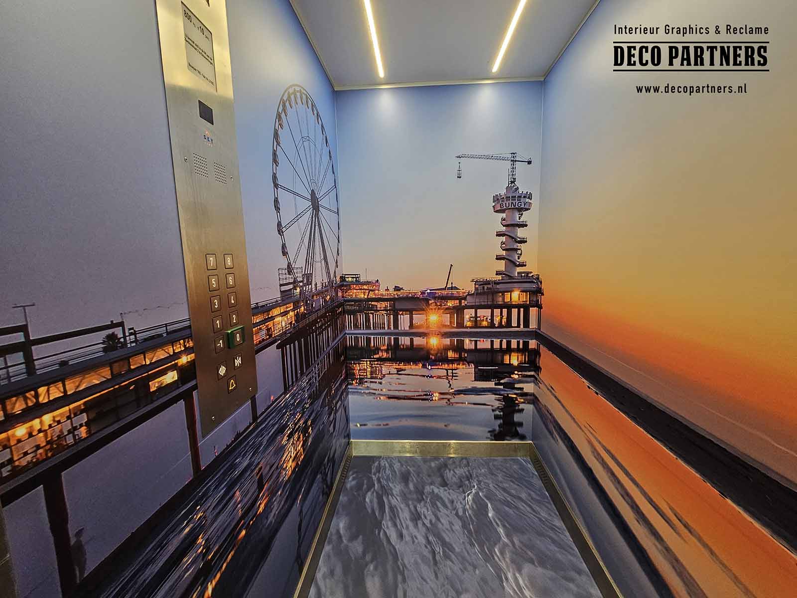 De binnenzijde van deze lift is volledig voorzien van hoogwaardige interieurfolie met een sfeervol strand- en zeezicht bij zonsondergang. Het ontwerp met pier en reuzenrad creëert een ontspannen vakantiesfeer en draagt bij aan de beleving van hotelgasten. Door wanden en vloer visueel op elkaar af te stemmen ontstaat een ruimtelijk en samenhangend geheel dat past bij de uitstraling van het hotel.